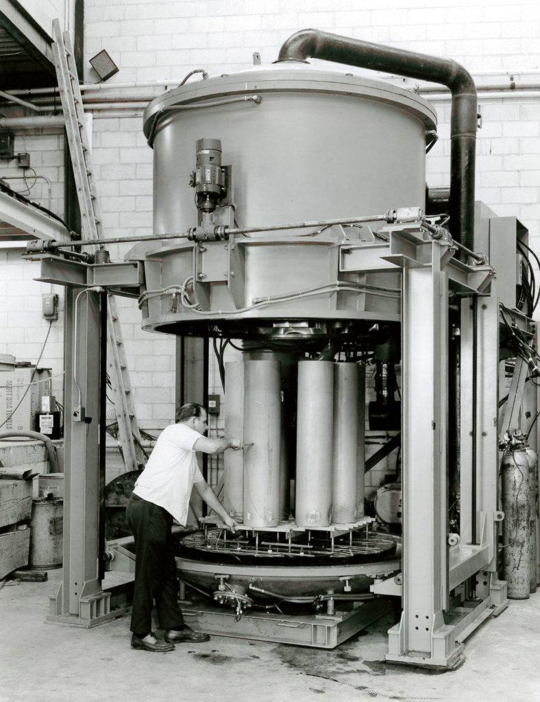 Vintage photo of a man operating a large vertical vacuum furnace
